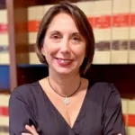 Amaya Mateos, bras croisés devant des étagères de livres juridiques