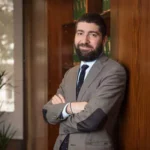 Daniel Huertas Montané, bras croisés, avec des livres juridiques en arrière-plan