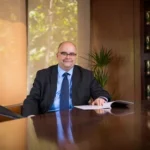 Francesc Guerrero González assis à son bureau, posture frontale, avec des livres derrière lui