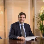 Lucas Rivière de Alvear assis à son bureau avec des documents ouverts et de la lumière naturelle