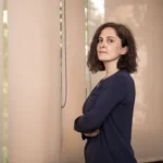 Mónica Ródenas Balaguer debout, bras croisés, à côté d’une fenêtre éclairée