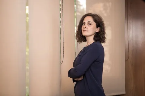 Mónica Ródenas Balaguer debout, bras croisés, à côté d’une fenêtre éclairée