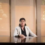 Natalia Díaz Solé assise sur une chaise, face à une table et des livres juridiques en arrière-plan