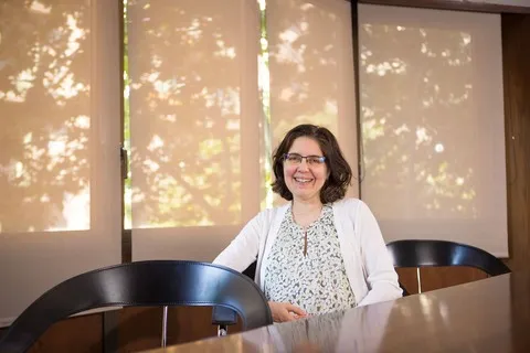 Raquel Rodríguez Miguélez assise à une table avec des étagères de livres juridiques en arrière-plan