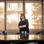 Rosario Sanchez Martos debout à côté d’une table de réunion avec des documents et des étagères en arrière-plan