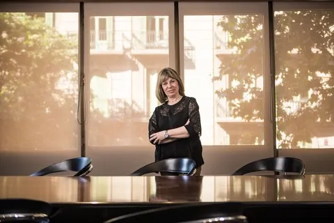 Rosario Sanchez Martos debout à côté d’une table de réunion avec des documents et des étagères en arrière-plan